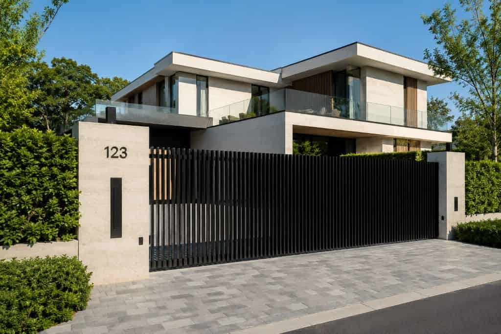 Modern luxury home with a black metal swing gate and secure driveway entrance