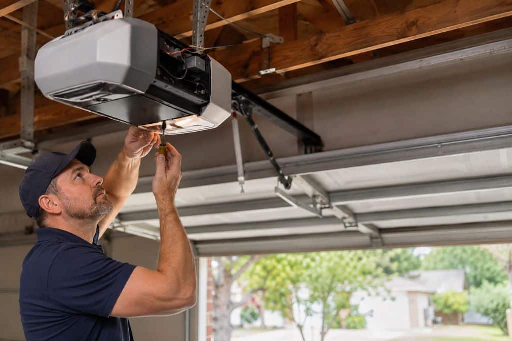 Technician repairing a ceiling-mounted garage door opener inside a residential garage in Canoga Park.